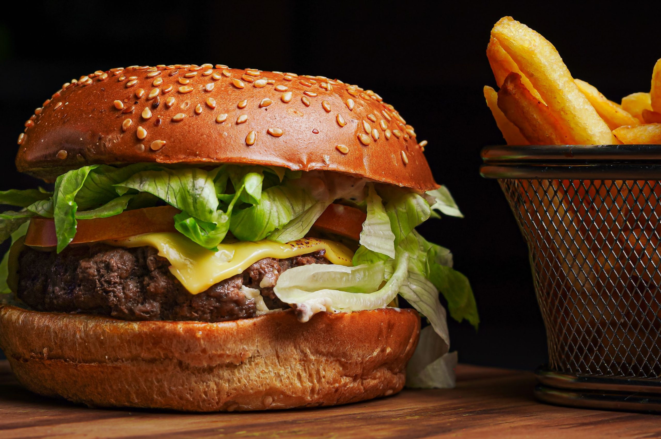 Delicious gourmet cheeseburger with fresh ingredients served alongside crispy fries in a basket.
