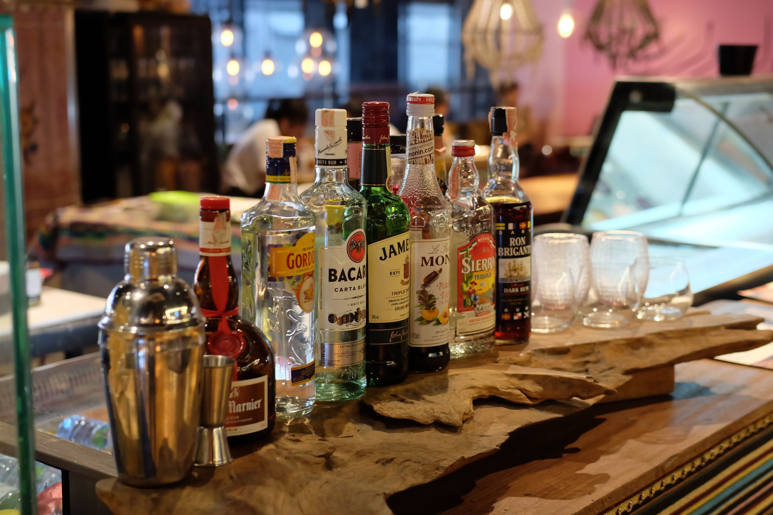 A selection of various liquor bottles and cocktail shaker on a bar counter.